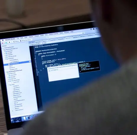 Person coding on laptop with blue screen